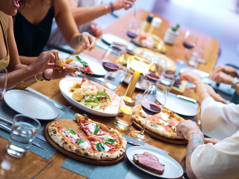 People enjoying pizza and other food