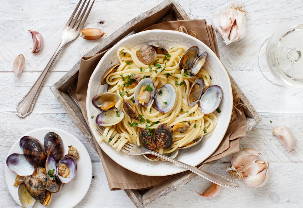 A Plate Of Italian Seafood Pasta Served With A Glass Of Pinot Grigio