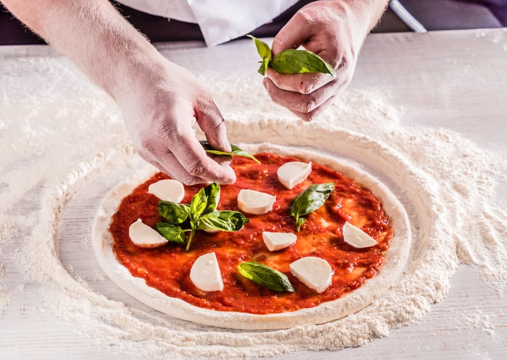 A Chef Putting Toppings On An Authentic Italian Pizza