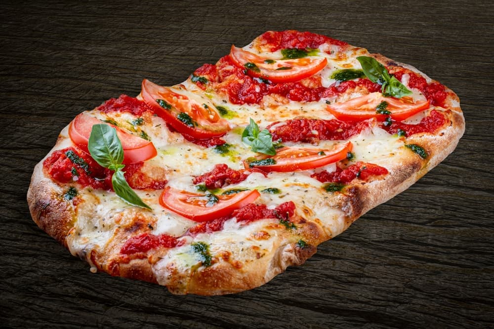 close up of a Roman style pizza, noted by its thin crust and light toppings